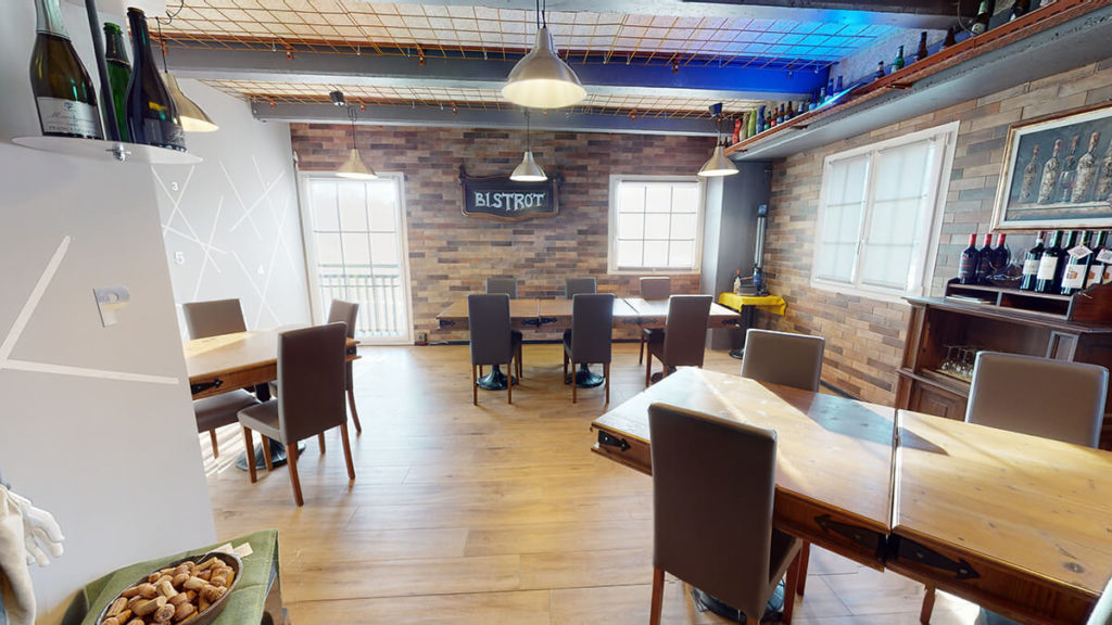 Interno e tavoli di un bistrot. Decorazione rustica con tavolo e pavimento in legno e mura in mattoni