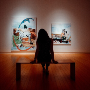 Silhouette di una donne che guarda due opere in una galleria d'arte