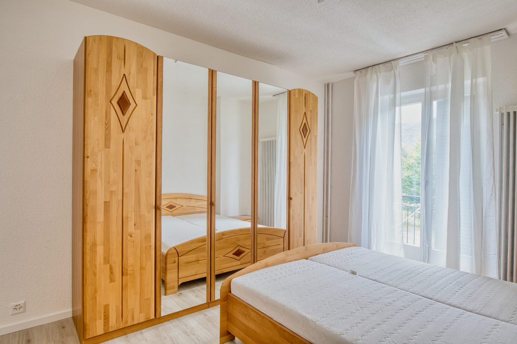 Camera da letto con arredamento in bamboo, letto matrimoniale e armadio con specchi